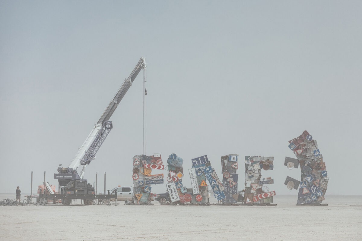 I’M FINE 2024, sculpture.  Road signs, fences ,gates, basketball ring and children swing from schoolyard. 8 x 35m
